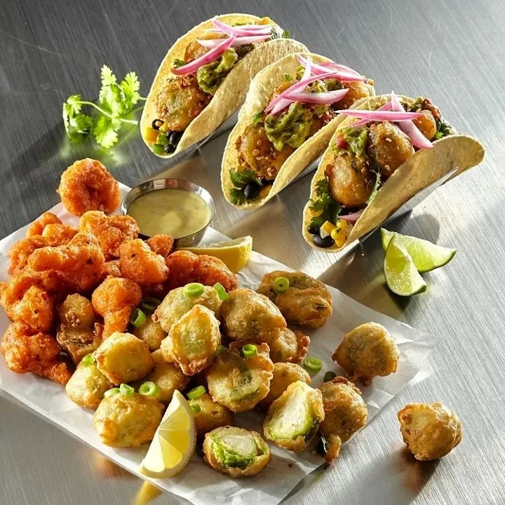 Crispy fried cauliflower, brussels sprouts, and vegetable tacos on metal.