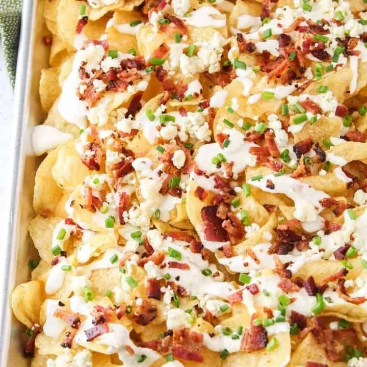 Loaded potato chips with creamy sauce, cheese, bacon, and chives.