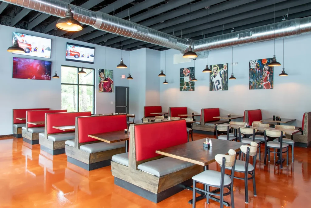 Sports bar with red booths, orange floor, and athlete art.