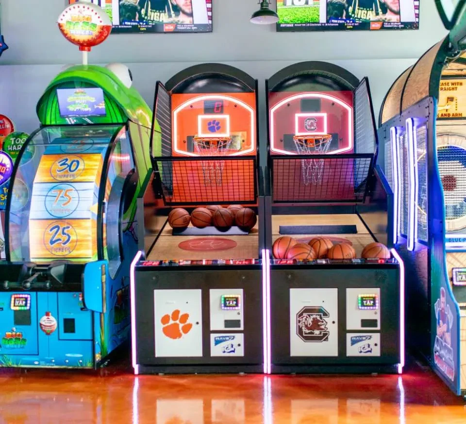 Vibrant sports-themed arcade with two basketball machines and other games.