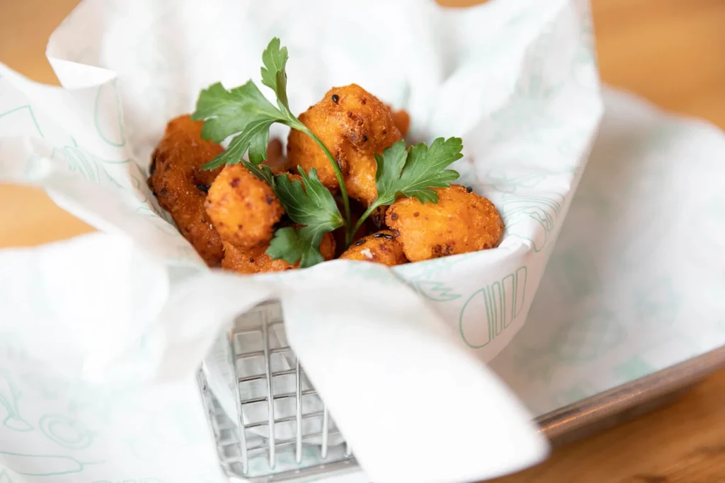 Golden, crispy deep-fried food in a wire basket with parsley.