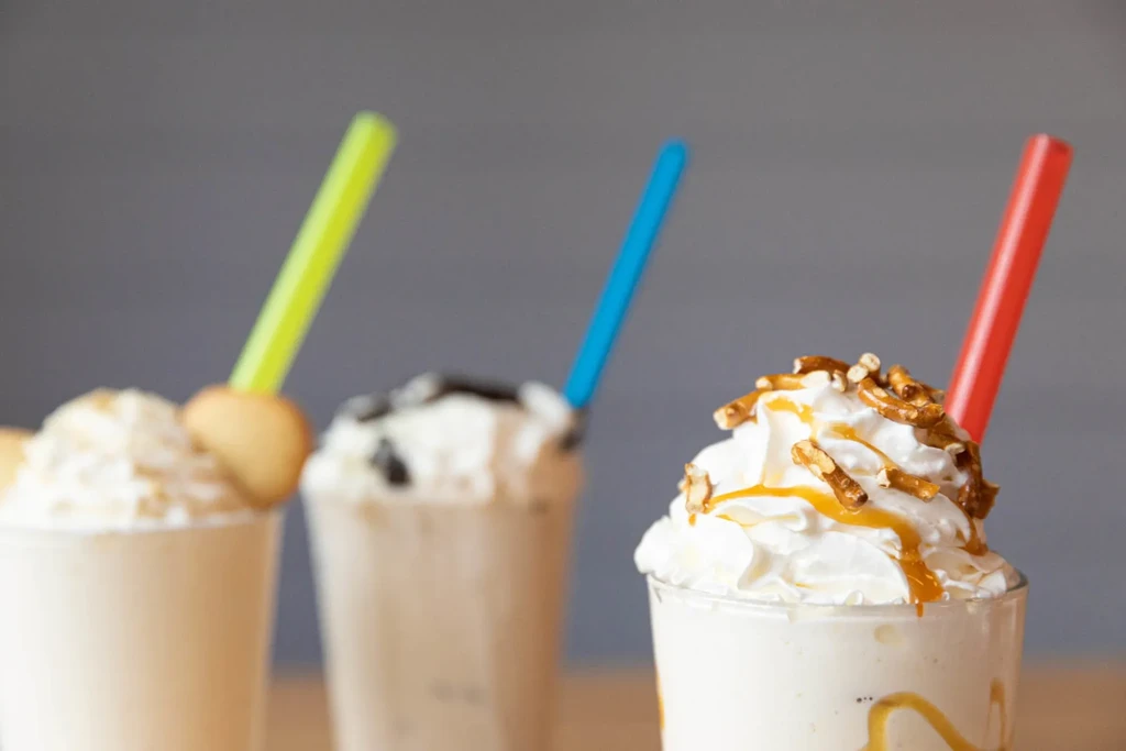 Three blended drinks with whipped cream, pretzel, caramel, and wafer toppings.