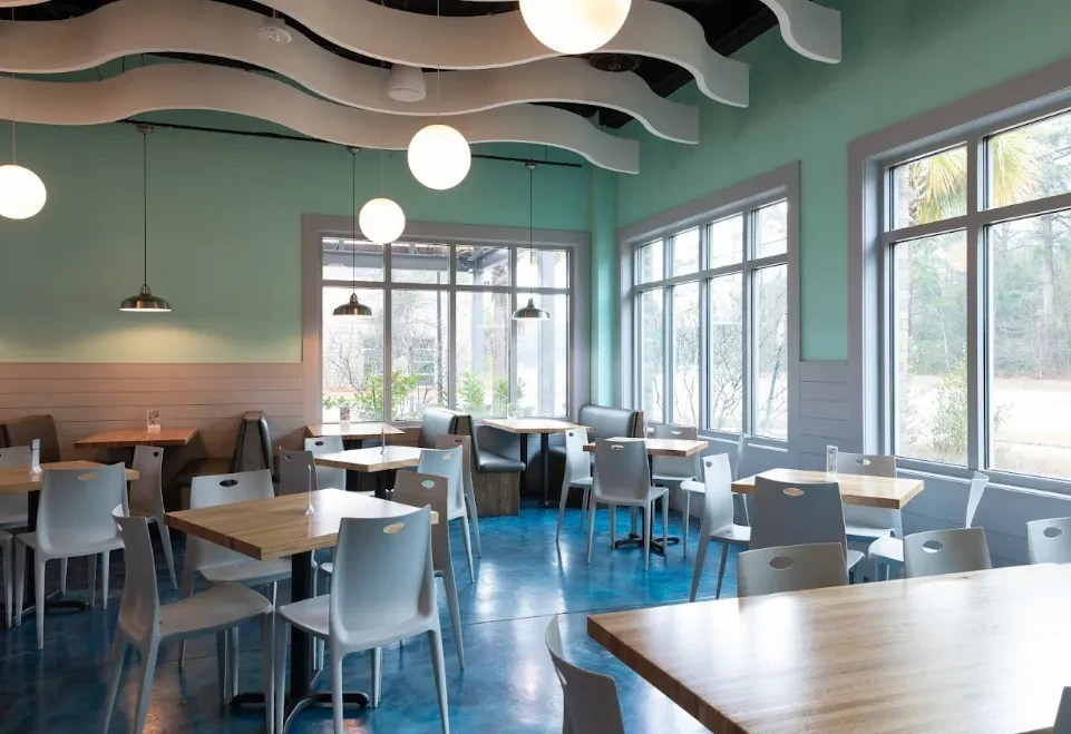Contemporary restaurant dining area with green walls, wood tables, wavy ceiling.