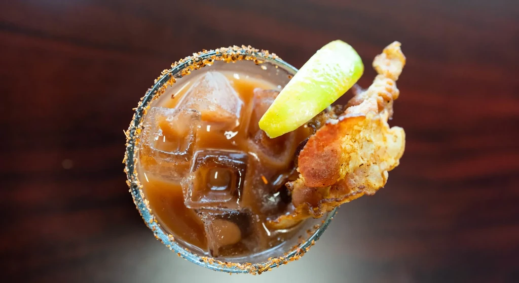 Top-down Bloody Mary cocktail with spiced rim, bacon, and cucumber.