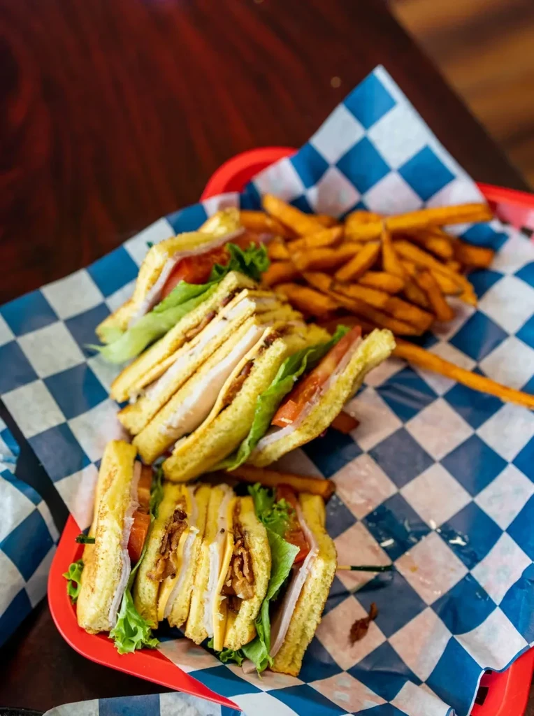 Two club sandwiches and golden fries in a red basket.