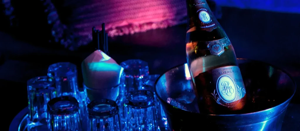 Cristal Roederer champagne, glasses, and glowing object under neon club lights.