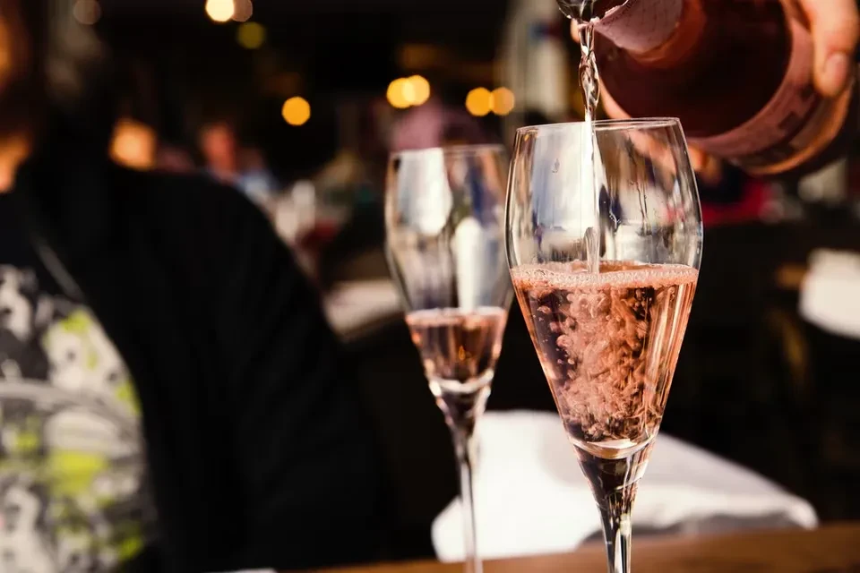 Pink sparkling wine pours into flute, creating bubbles, restaurant setting.