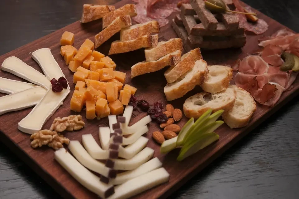 Charcuterie and cheese board with meats, cheeses, fruit, nuts, and bread.