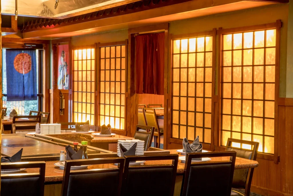 Empty Japanese restaurant interior with hibachi tables and shoji screens.