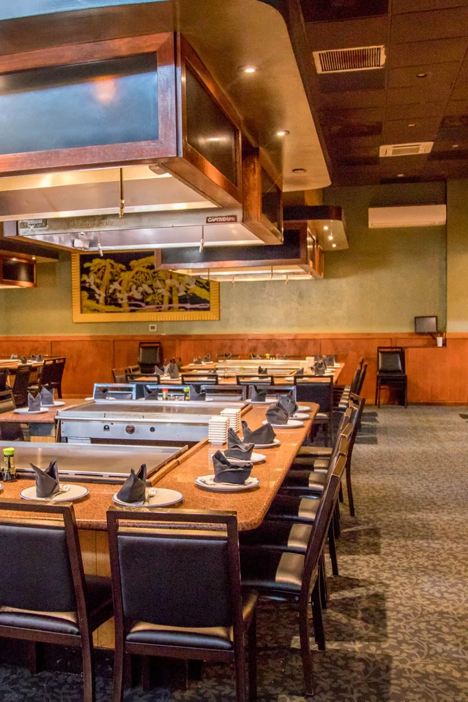 Empty hibachi restaurant dining area with multiple set teppanyaki grills.