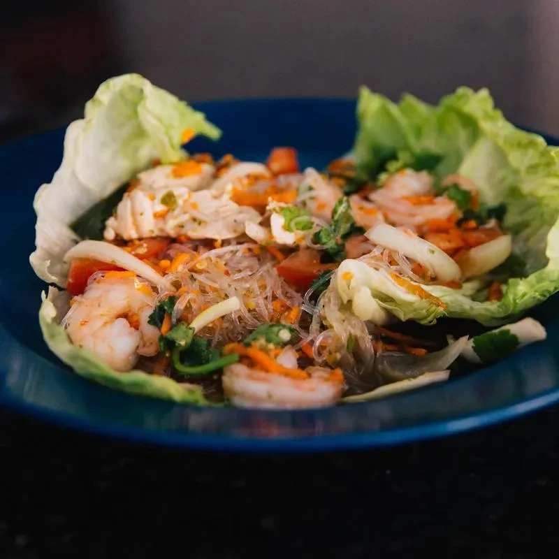 Vibrant Thai glass noodle salad with shrimp, vegetables, and lettuce lining.