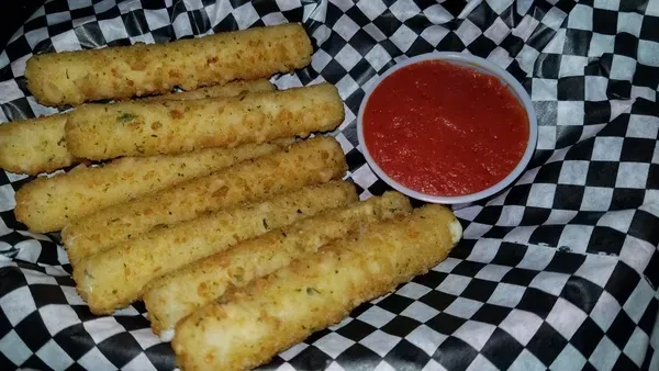 Crispy mozzarella sticks piled in a basket with marinara sauce.