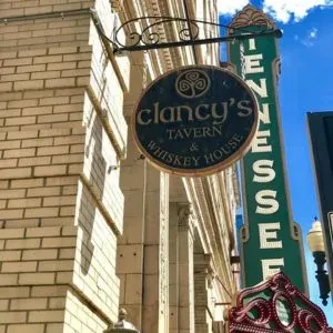 Circular "Clancy's Tavern" sign on brick building, Tennessee sign visible.