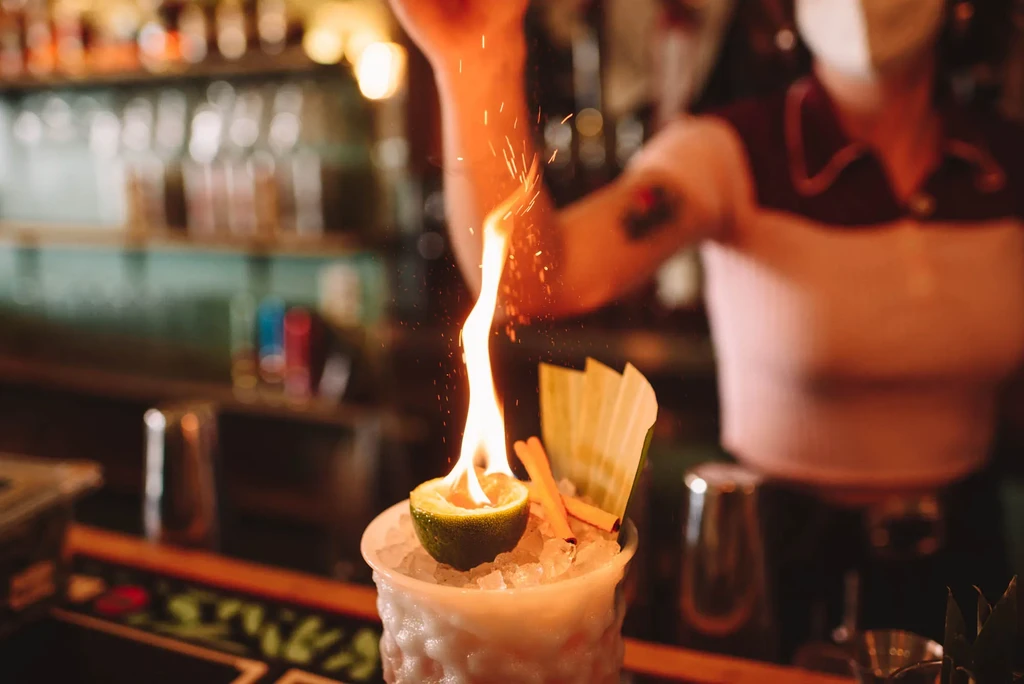 Flaming lime cocktail with sparks, prepared by a bartender.