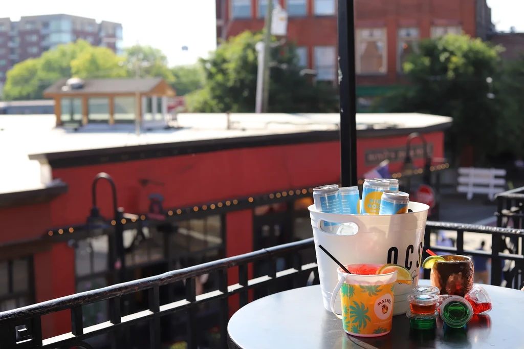 Colorful cocktails, shots, and canned drinks on an outdoor patio table.