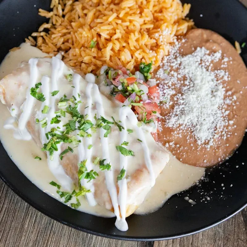 Artfully arranged Mexican enchilada, rice, refried beans, and pico de gallo.