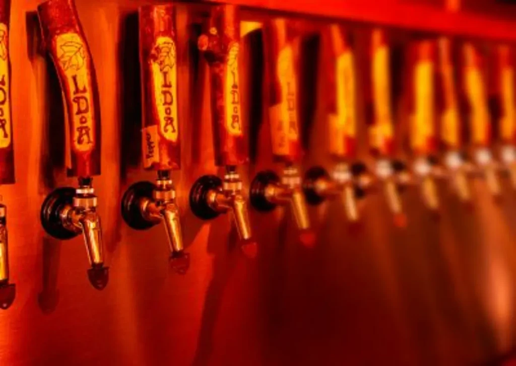 Close-up of several rustic wooden beer taps with text in warm light.