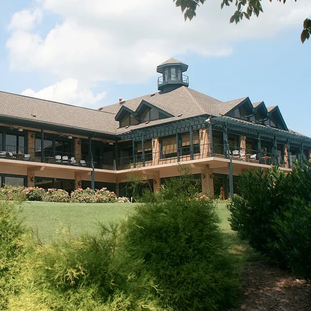 Multi-story building with cupola, wrap-around balcony, and green landscaping.