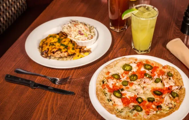 Restaurant table with grilled protein, flatbread, margarita, and iced tea.