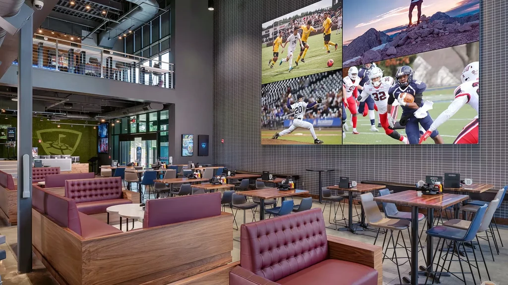 Modern Topgolf venue with diverse seating and a large sports video wall.