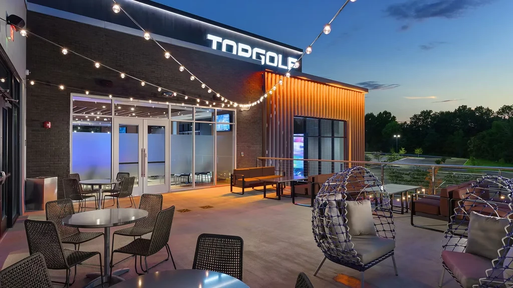 Topgolf patio at dusk with string lights and various seating.