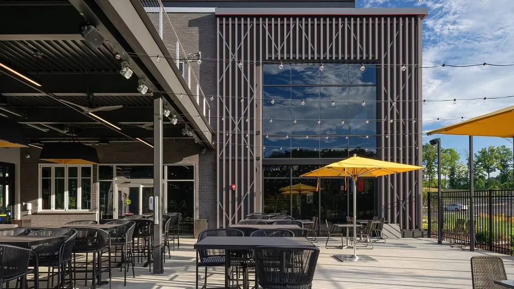 Modern building's empty outdoor patio features covered seating and umbrellas.