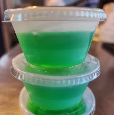 Two stacked clear conical containers with green liquid and white foam.