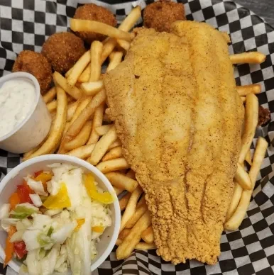 Fried fish, french fries, hushpuppies, tartar sauce, and coleslaw in a basket.
