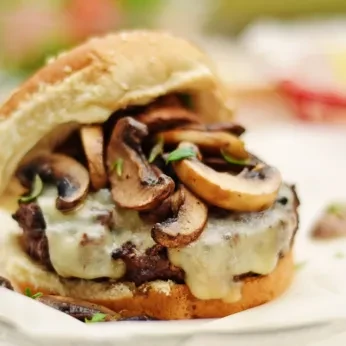 Close-up of a beef mushroom and Swiss burger with herbs.