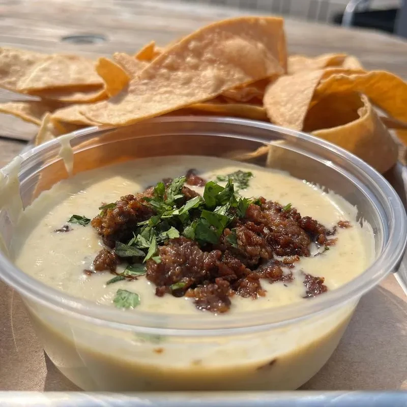 Creamy queso dip topped with chorizo and cilantro, with tortilla chips.