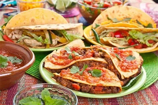 Vibrant Mexican food spread with tacos, quesadillas, and salsas.