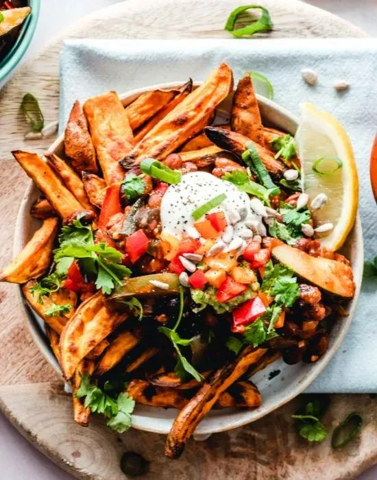 Sweet potato fries topped with chili, guacamole, fresh herbs, and lemon.