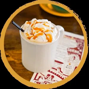 White mug with caramel whipped cream drink, black straw, and skull motif.