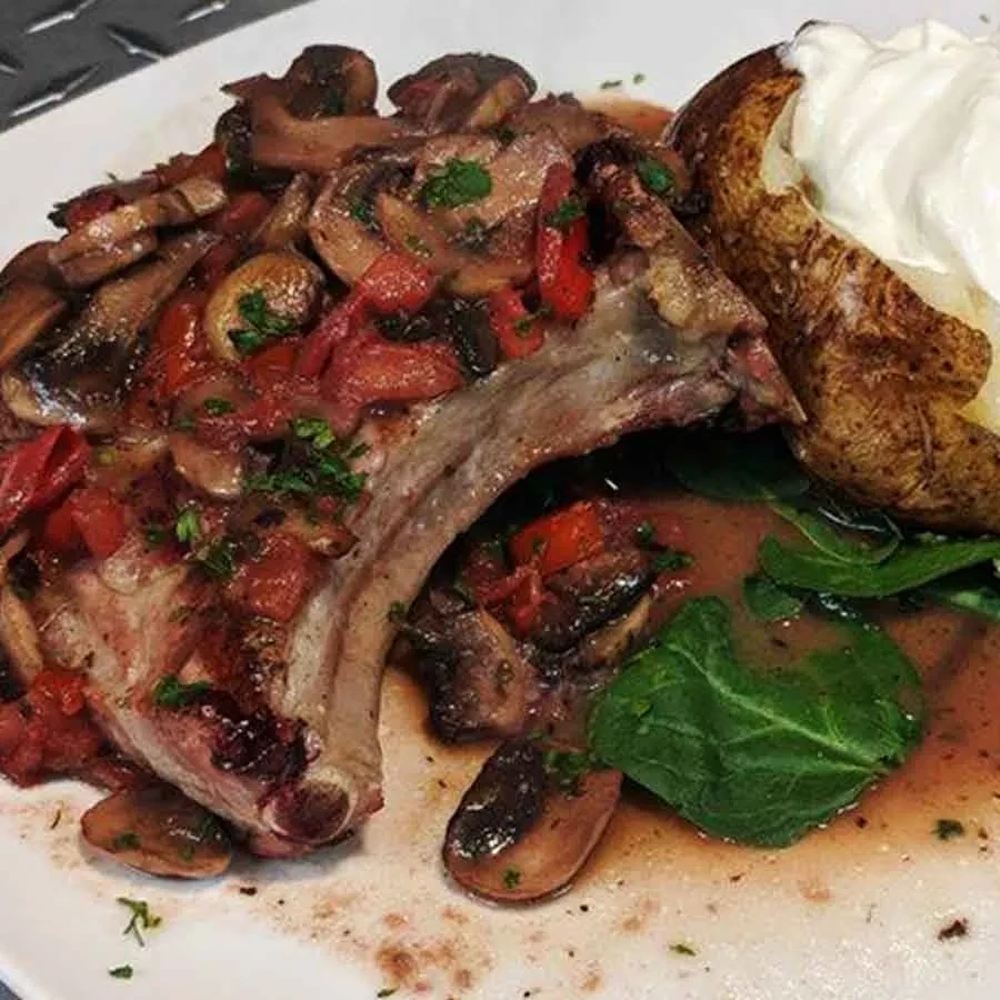 Bone-in meat with mushrooms, baked potato, sour cream, and spinach.