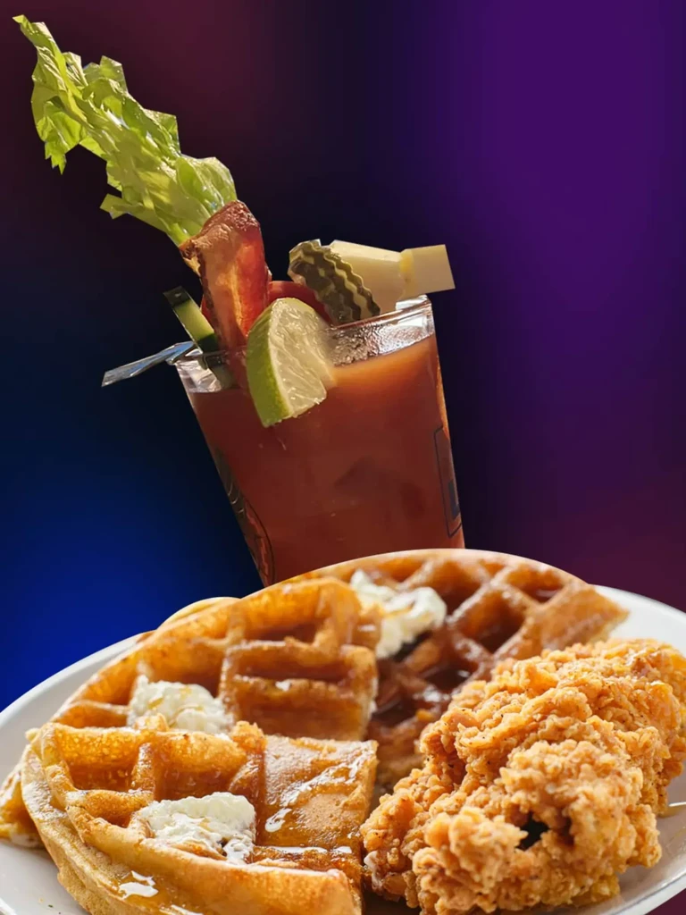 Close-up of chicken and waffles with an elaborately garnished Bloody Mary.