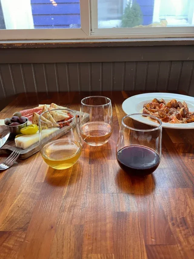 Charcuterie, wine, and pasta dish on a rustic restaurant table.