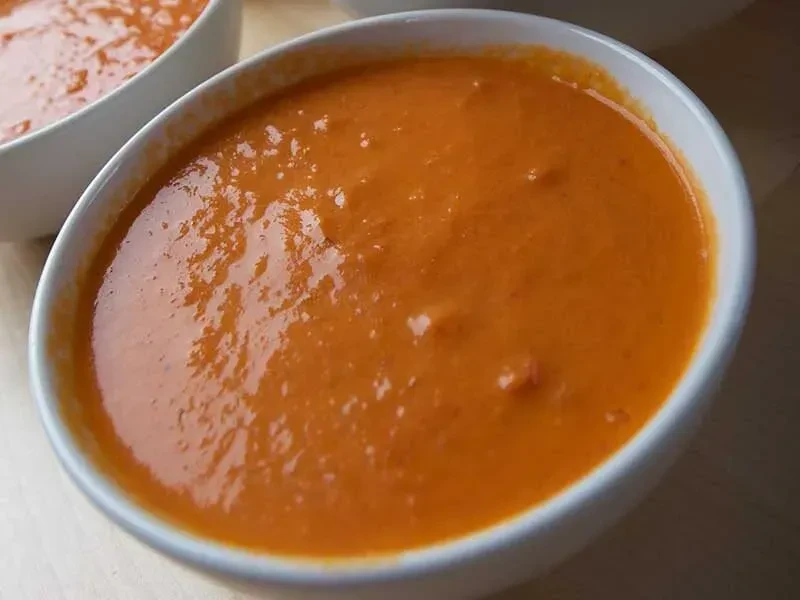 Close-up of white bowl with thick reddish-orange soup or dip.