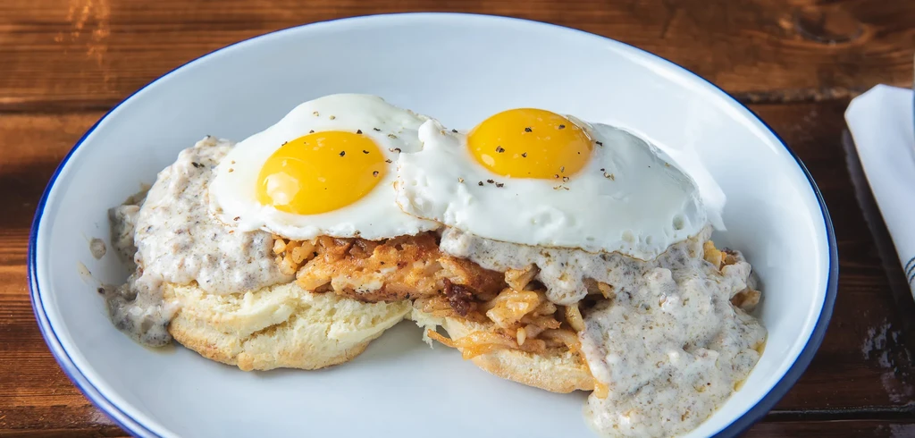 Biscuits, sausage gravy, hash browns, and two sunny-side-up eggs.