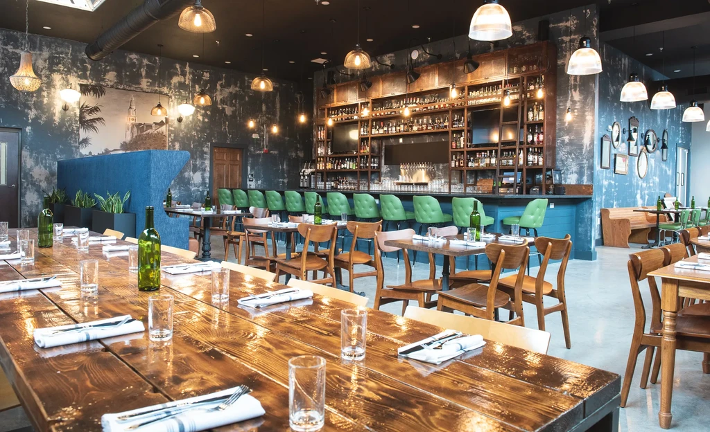Elegant empty restaurant interior with a bar, long table, and wall mural.
