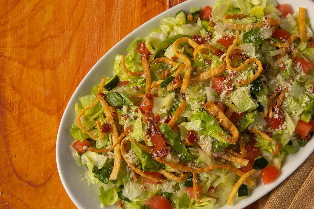 Overhead shot: Salad with lettuce, tomatoes, cucumber, bacon, cheese, wontons.