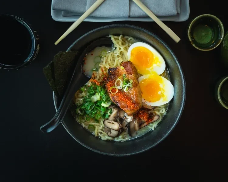 Overhead shot of ramen with pork, eggs, noodles, nori, and greens.