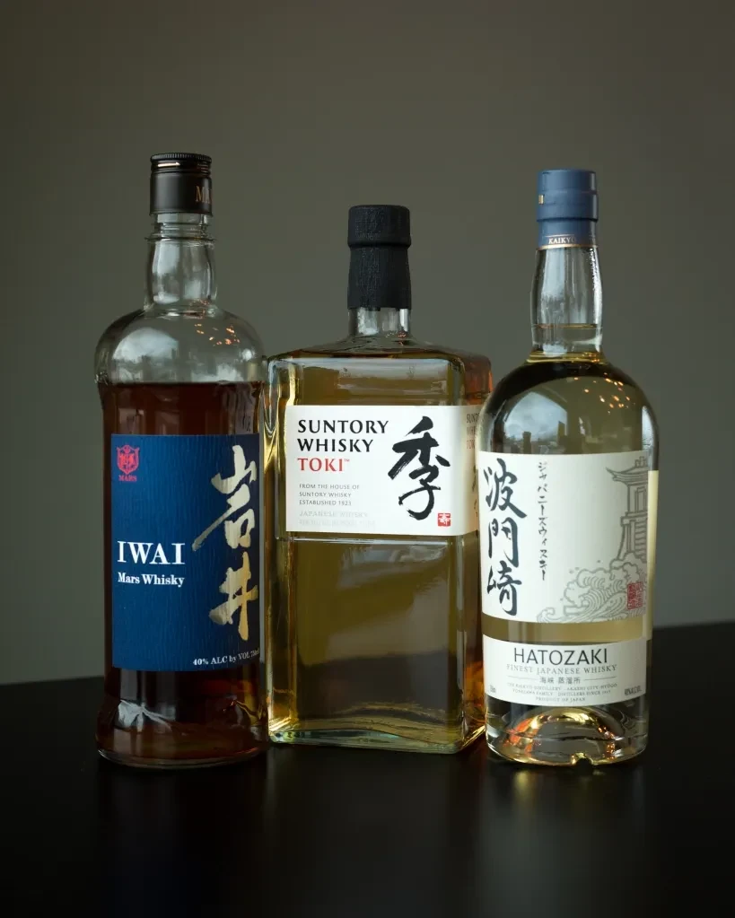 Three bottles of Japanese whisky: Iwai, Suntory Toki, and Hatozaki.