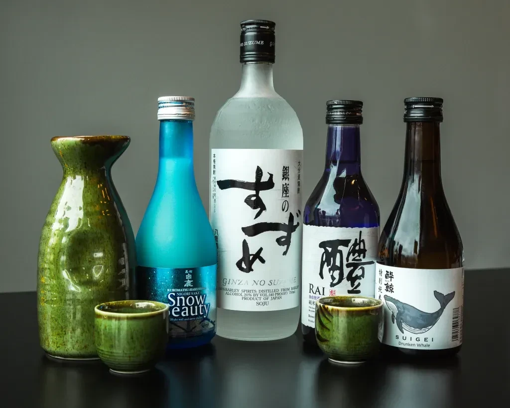 Five Japanese sake bottles and green ceramic serving ware.