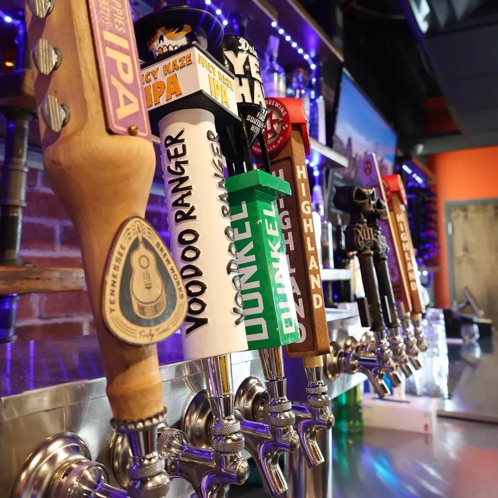 Row of ornate beer tap handles under blue LED lighting.