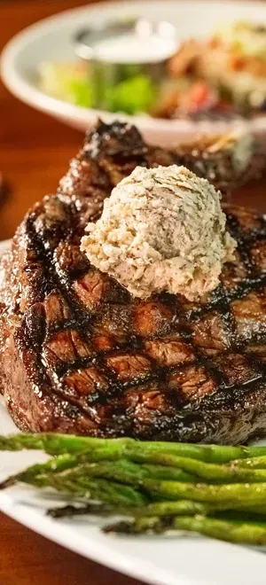 Grilled steak with melting butter and asparagus on a white plate.