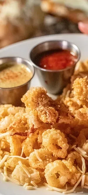 Plate of golden-brown breaded seafood with two dipping sauces.