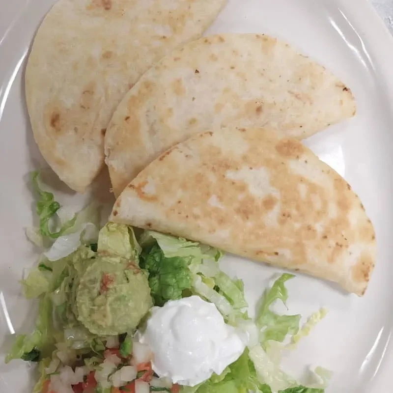 Three folded tortillas, lettuce, guacamole, sour cream, and pico de gallo.