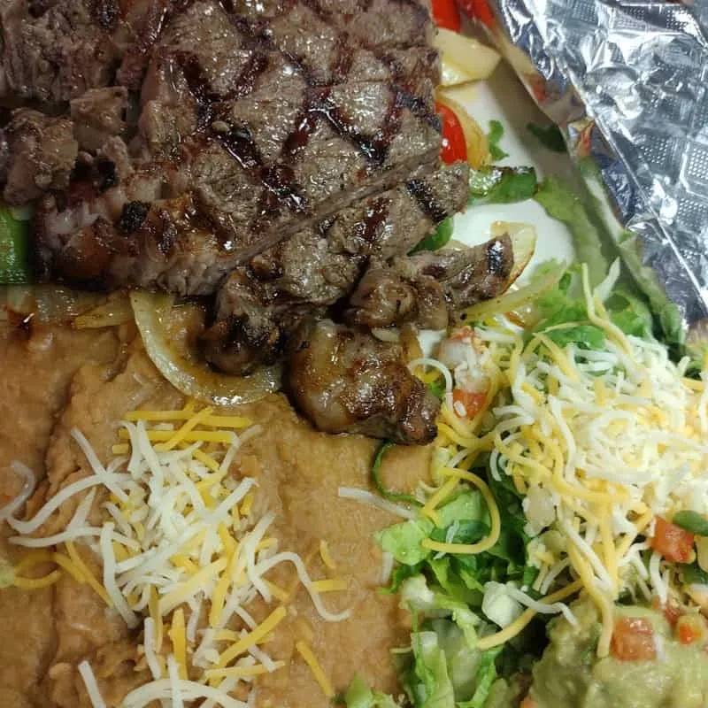 Mexican-style meal with grilled steak, beans, salad, and guacamole.
