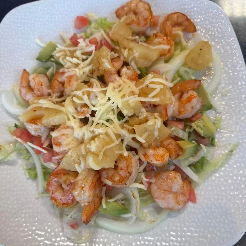 Shrimp salad with pineapple, cheese, tomatoes, lettuce, and dressing.