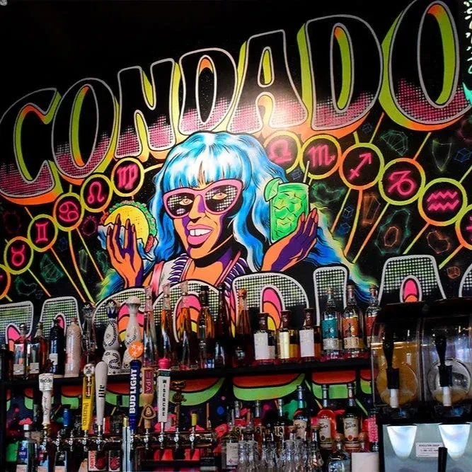 Condado bar mural: pop-art woman with blue hair, taco, and drink.